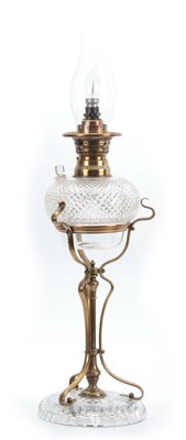 Lot 596 - AN ART NOUVEAU BRASS AND CUT GLASS OIL LAMP...