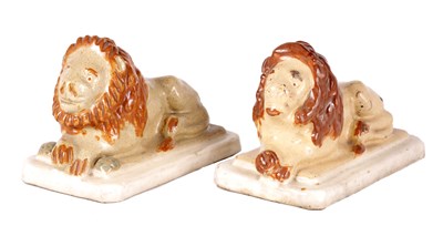 Lot 28 - A PAIR OF 19TH CENTURY GLAZED PAINTED STONEWARE RECUMBENT LIONS
