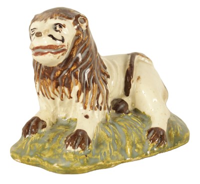 Lot 32 - AN EARLY 19TH CENTURY STAFFORDSHIRE SCULPTURE OF A RECUMBENT LION