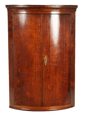 Lot 1141 - A MID 18TH CENTURY FIGURED OAK BOW FRONT CORNER CUPBOARD
