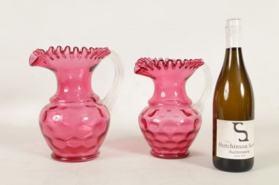 Lot 4 - A GRADUATED PAIR OF 19TH CENTURY STYLE OVERSIZED CRANBERRY GLASS JUGS