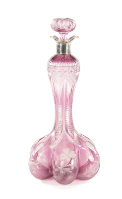 Lot 26 - ATTRIBUTED TO STEVENS AND WILLIAMS - AN INTAGLIO CUT GLASS AMETHYST TINTED DECANTER OF ORGANIC FORM OF 6 LOBES