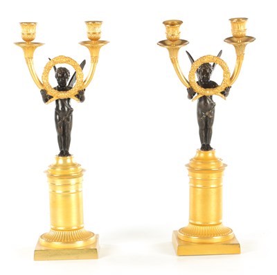 Lot 636 - A PAIR OF REGENCY STYLE TWO BRANCH BRONZE AND CAST BRASS WINGED CHERUB CANDLESTICKS