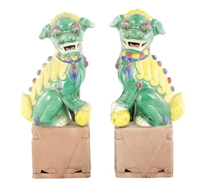 Lot 224 - A PAIR OF CHINESE SEATED FOO DOGS ON BROWN PEDESTAL BASES
