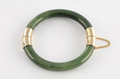 Lot 178 - AN ORIENTAL SAGE GREEN JADE AND GOLD METAL MOUNTED BANGEL
