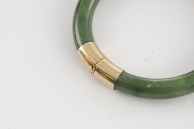 Lot 178 - AN ORIENTAL SAGE GREEN JADE AND GOLD METAL MOUNTED BANGEL