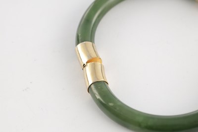 Lot 178 - AN ORIENTAL SAGE GREEN JADE AND GOLD METAL MOUNTED BANGEL