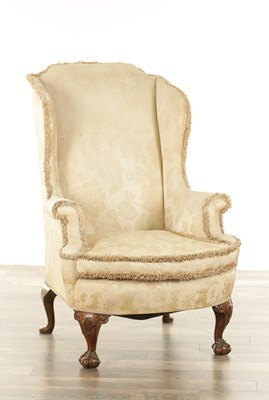 Lot 1189 - A GEORGIAN STYLE CARVED WALNUT WING-BACK UPHOLSTERED ARMCHAIR