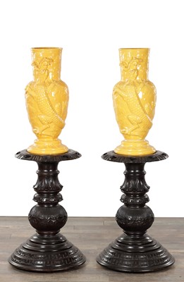 Lot 545 - A PAIR OF CHINESE YELLOW GLAZED RELIEF MOULDED DRAGON VASES ON CARVED HARDWOOD STANDS