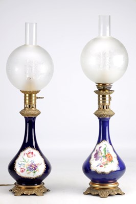 Lot 976 - A PAIR OF EARLY 20TH CENTURY FRENCH PORCELAIN OIL LAMPS CONVERTED TO ELECTRICITY WITH FROSTED GLASS SHADES