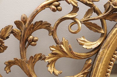 Lot 1588 - A GEORGE III CARVED GILTWOOD OVAL HANGING MIRROR WITH FLOWER BASKET CRESTING