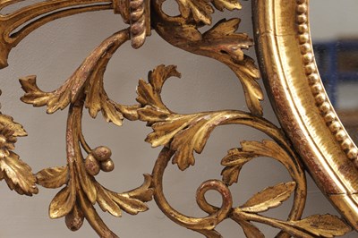 Lot 1588 - A GEORGE III CARVED GILTWOOD OVAL HANGING MIRROR WITH FLOWER BASKET CRESTING