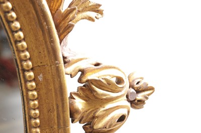 Lot 1588 - A GEORGE III CARVED GILTWOOD OVAL HANGING MIRROR WITH FLOWER BASKET CRESTING