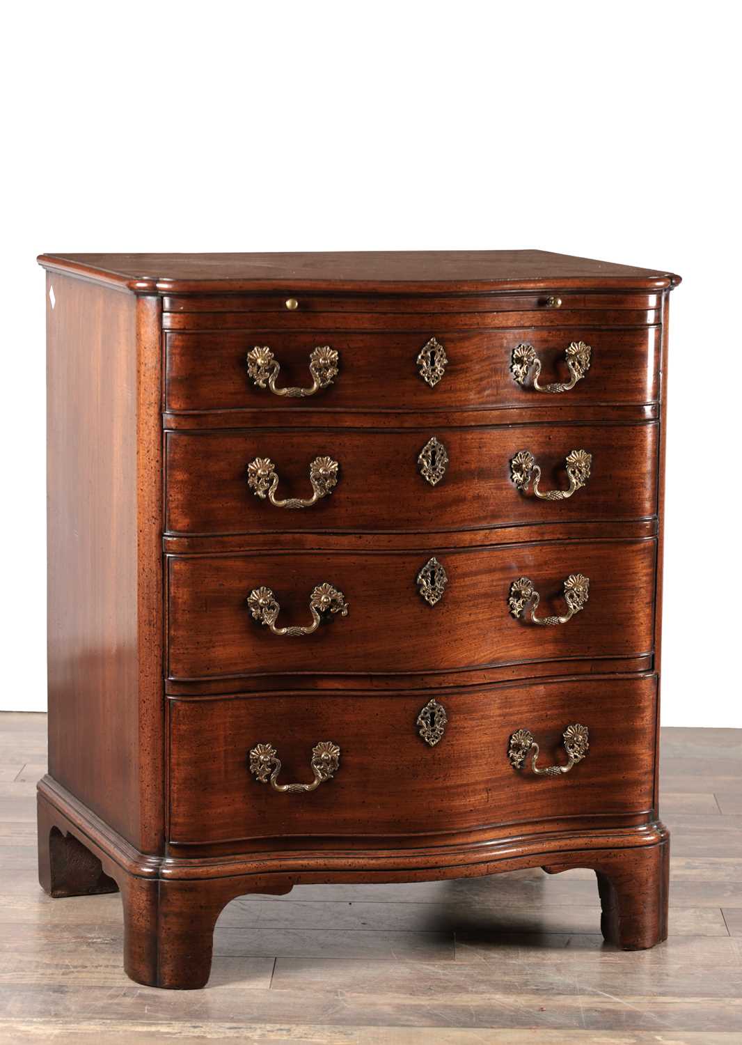 Lot 1515 - AN UNUSUAL GEORGE III STYLE MAHOGANY SERPENTINE CHEST OF DRAWERS WITH BRUSHING SLIDE