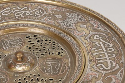 Lot 776 - A 19TH CENTURY ISLAMIC BRASS AND SILVER INLAID WASH BASIN WITH CENTRAL PIERCED STRAINER