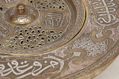 Lot 776 - A 19TH CENTURY ISLAMIC BRASS AND SILVER INLAID WASH BASIN WITH CENTRAL PIERCED STRAINER