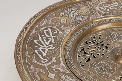 Lot 776 - A 19TH CENTURY ISLAMIC BRASS AND SILVER INLAID WASH BASIN WITH CENTRAL PIERCED STRAINER