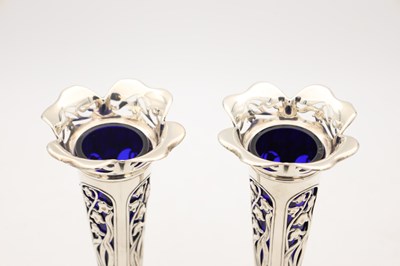 Lot A PAIR OF EDWARDIAN ENGLISH PIERCED SILVER SPILL VASES WITH BLUE GLASS LINERS