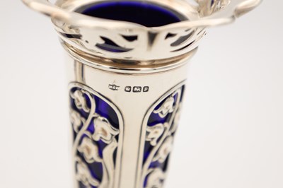 Lot A PAIR OF EDWARDIAN ENGLISH PIERCED SILVER SPILL VASES WITH BLUE GLASS LINERS