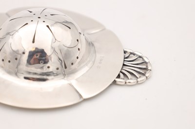 Lot AN EARLY 20TH CENTURY GEORG JENSEN DANISH SILVER TEA STRAINER AND STAND