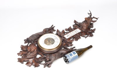 Lot 11 - A 19TH CENTURY BLACK FOREST CARVED LINDEN WOOD ANEROID HANGING BAROMETER